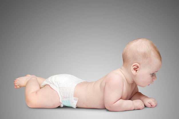 灰色の背景に横たわっている6ヶ月の幼児の子供の赤ちゃん