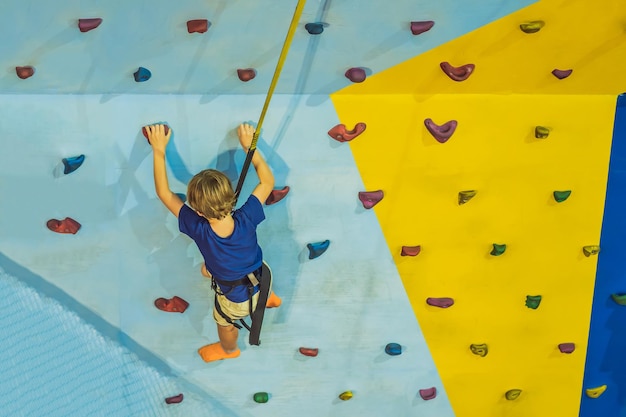 6 years old child climbing on a wall in a climbing center