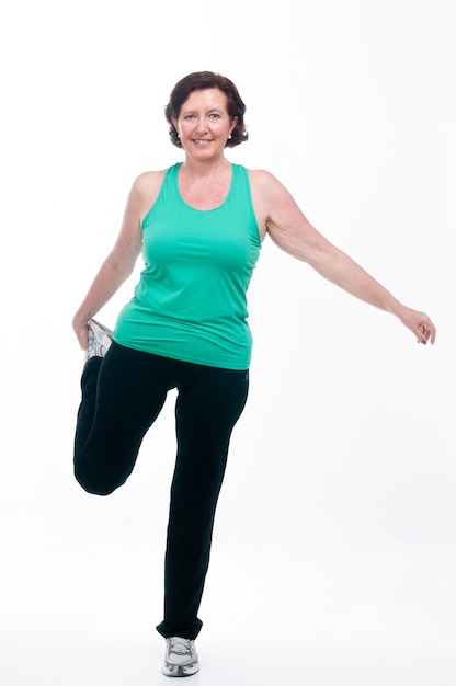 60 year old senior woman doing gymnastics on white background