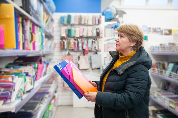 Donna di 60 anni che sceglie le cartelle per i documenti in cartoleria