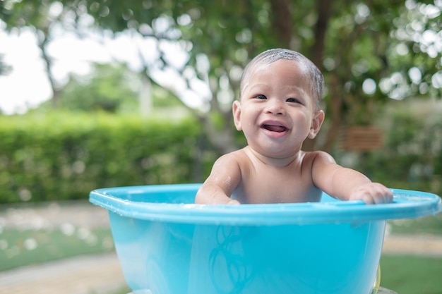 屋外で良い気分でお風呂に入っている生後7ヶ月の笑顔の赤ちゃん