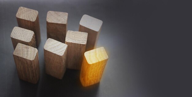 7 same and 1 different wooden blocks standing on black background Leadership and team abstract business concept