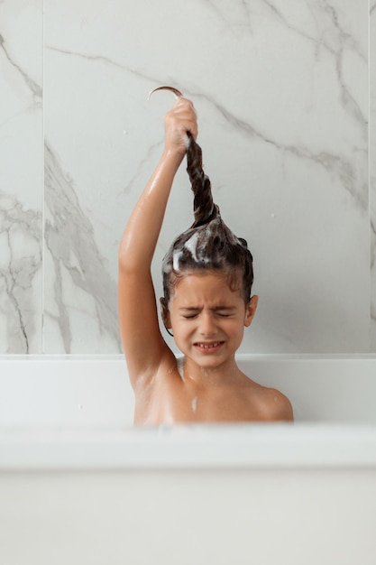 감정을 보여주는 거품 목욕을 하는 7세 소녀