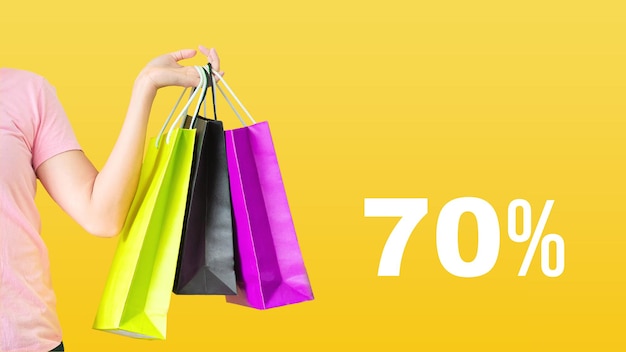 70% discount.Sale with female hands holding shopping bags on yellow background. Black Friday and sale concept.