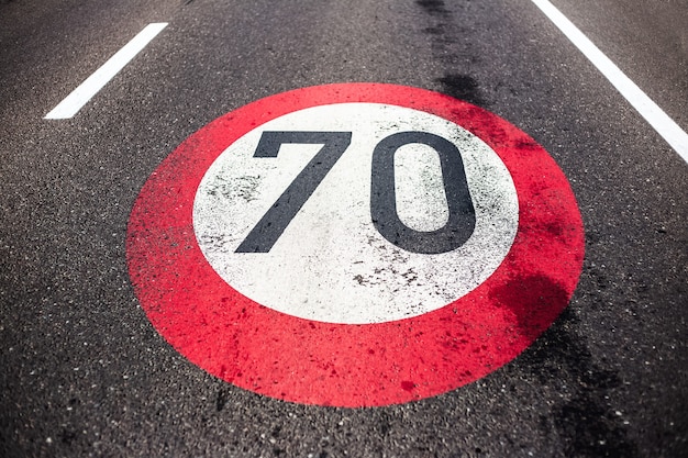 Фото Знак ограничения скорости 70 км / ч нарисован на асфальтированной дороге.