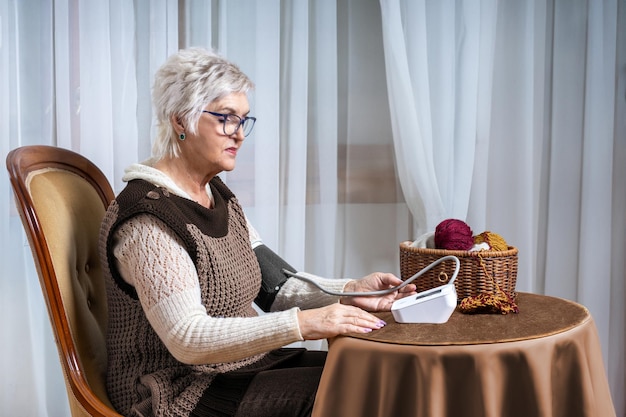 70歳の女性が自動トノメーターで血圧を測る