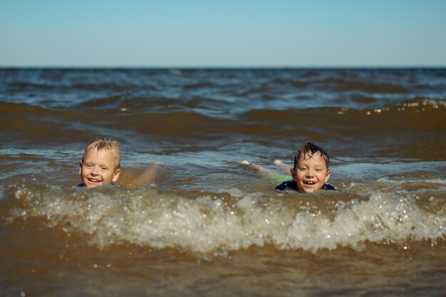 78 jaar oude schattige blanke jongens zwemmen in de zee met grote spatten in golven