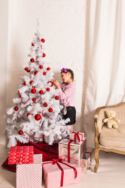 8 jaar oud meisje die Kerstboom thuis verfraaien.