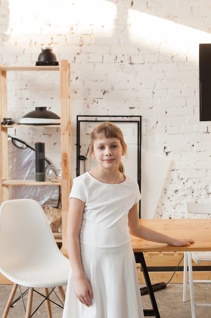 8-jarig meisje in witte jurk in een helder schoolinterieur