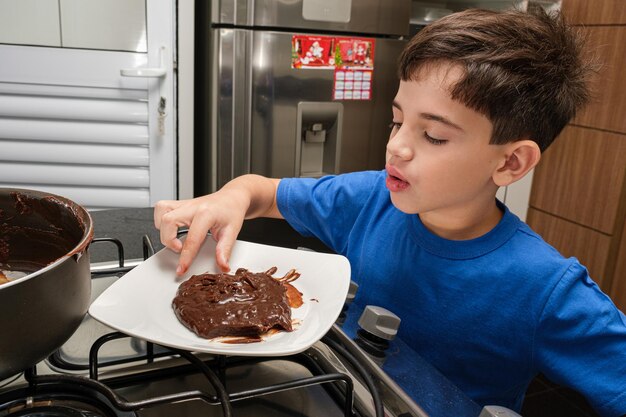 8-летний ребенок берет пальцами бразильскую сладость бригадейру.