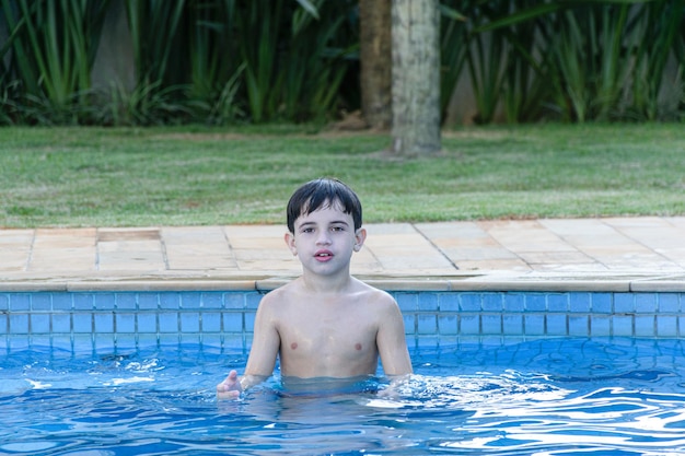 8 year old kid in the pool, waiting for the ball to be thrown for him to catch.