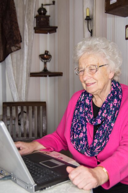 Photo 80 year old woman is risk group for covid 19 on the laptop against isolation with her family ban