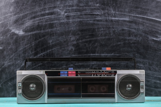 Photo 80s retro old school portable stereo radio cassette recorder on the background of blackboard