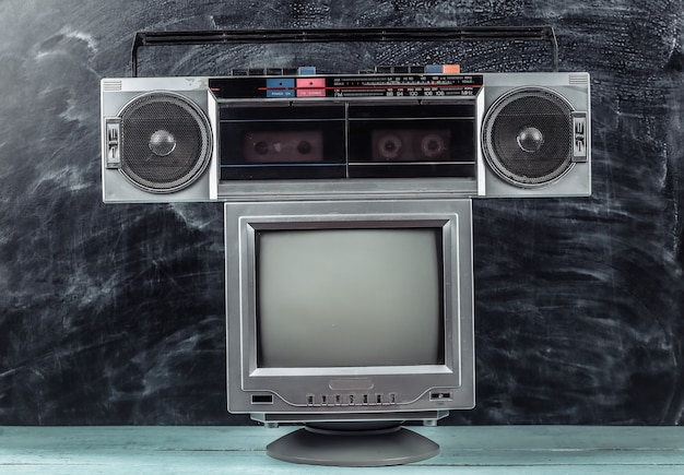 80s Retro outdated portable stereo radio cassette recorder, tv set  on blackboard background