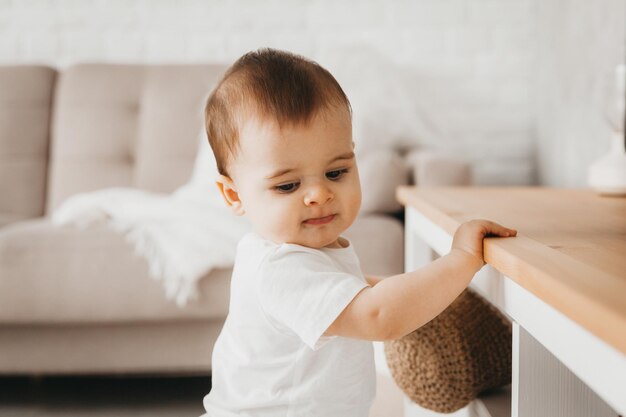 9 maanden oude baby staat en houdt zich vast aan een plank