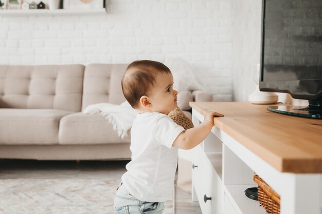 9 month old baby stands and holds on to a shelf