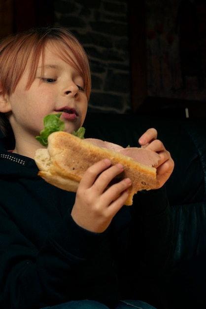 9 year old boy eating a big baguette sandwich