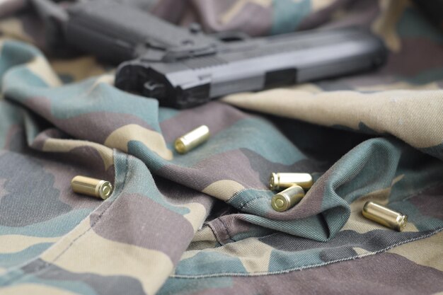 Foto i proiettili e la pistola da 9 mm giacciono su un tessuto verde mimetico piegato un set di articoli per il tiro a segno o un kit di autodifesa