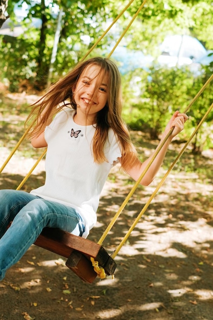 a 9yearold girl of Slavic appearance laughs merrily and rides on a swing