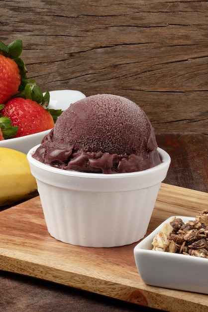 AÃ§aÃ­ in a white bowl with banana, granola and strawberry.