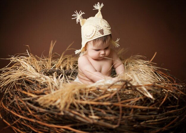 Foto a baby is sitting in a nest with hay and a hat that says  baby