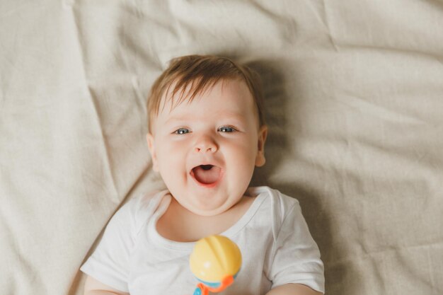 写真 綿のベッドの上に歯磨き器とラッテルを持った赤ちゃん 歯磨き 子供の記事のコピースペース