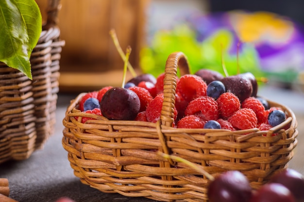 Фото Корзина ягод смешанного лета голубика, вишня, поленика здоровой пищи селективного внимания.