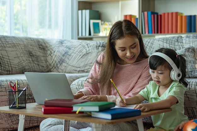 写真 美しいアジアの母親は自宅で子供の世話や教育をしている間忙しいwfhです