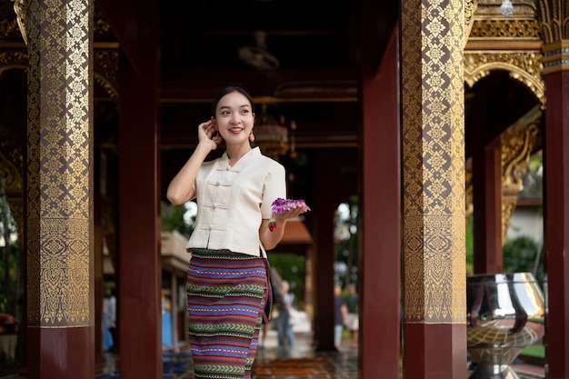 Фото Красивая азиатская женщина в традиционном платье с гирляндью в руках стоит в храме