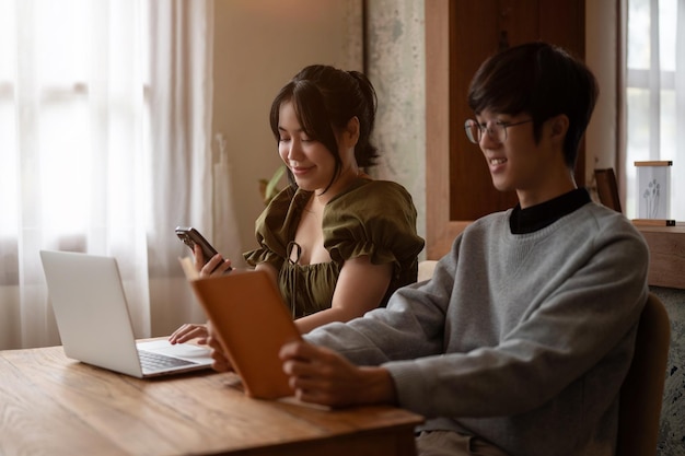 사진 아름다운 아시아 여성이 주말에 커피숍에서 남자 친구와 원격으로 일하고 있습니다.