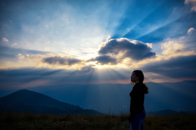 Фото Красивая азиатская женщина стоит и смотрит на закат с видом на горы вечером