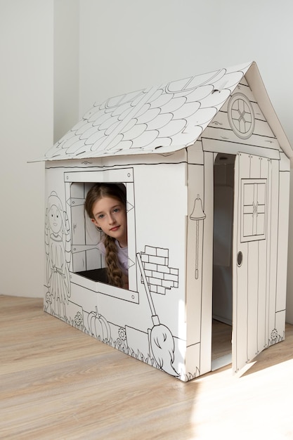 Фото Красивая девушка смотрит в окно из картонного белого дома