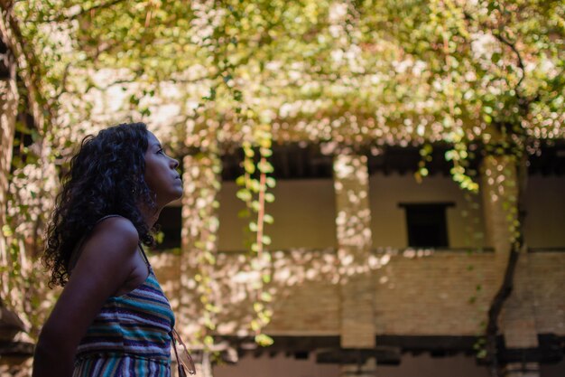 写真 植物で覆われた構造物を見上げている長い巻きの美しいラテン系女性