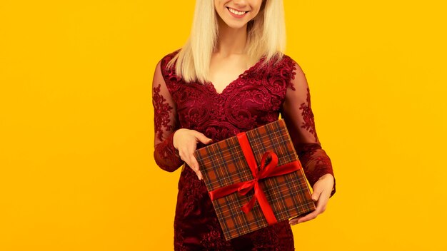 赤いドレスを着た美しいセクシーな女の子は、贈り物を手に持っています。クリスマスや新年のお祝い