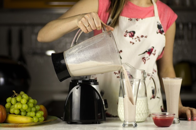 Фото Красивая женщина готовит молочный коктейль с фруктами на кухне