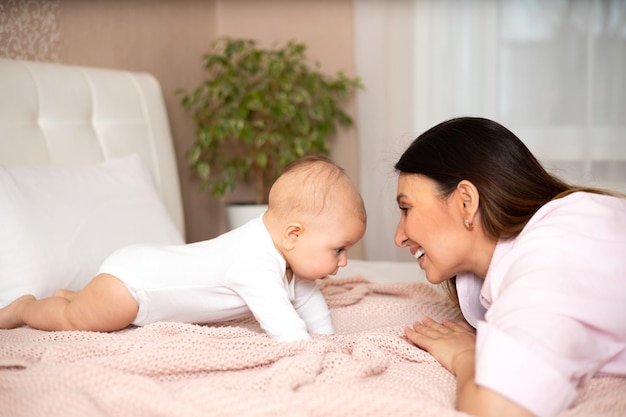 写真 美しい若い母親がベッドで赤ちゃんと遊んだり抱きしめたりする愛の母性ライフスタイル