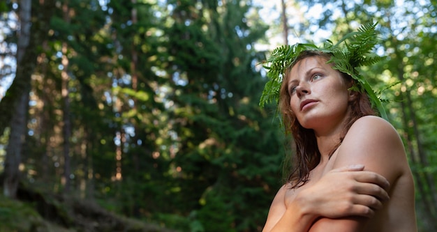 사진 숲 강에서 자연을 즐기는 그녀의 머리에 고사리 화환을 가진 아름다운 젊은 누드 여자