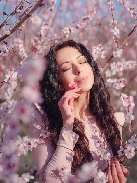 Красивая молодая женщина возле цветущего весеннего вишневого дерева. идея и концепция обновления, заботы о себе и счастья