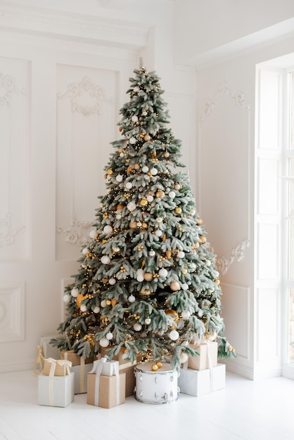 Фото Красиво украшенная комната с рождественской елкой с подарками под интерьером рождественская волшебная светящаяся елка новый год мягкий выборочный фокус