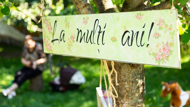 Фото Знак дня рождения, висящий на дереве, с румынской надписью «la multi ani-happy birthday».