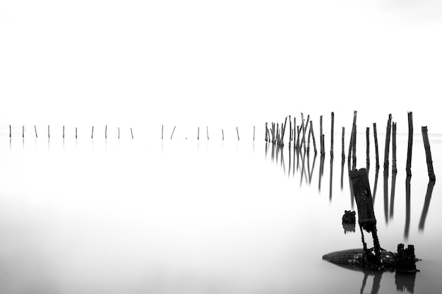 사진 울타리와 안개가 자욱한 호수의 흑백 사진.