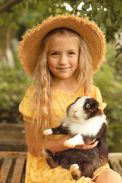 Фото Блондинка в соломенной шляпе в желтом платье держит кролика