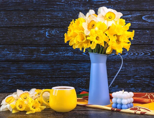 写真 黄色いテーブルクローツの上に青い花瓶に花束の花束 黄色いカップ 青いろうそく