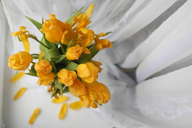 写真 窓辺の花瓶に黄色いチューリップの花束。黄色いチューリップの花から女性の日への贈り物。窓際の花瓶に美しい黄色い花。