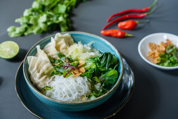 写真 テーブルの上には、餃子の入ったボウルと麺の入ったボウルと唐辛子の入ったボウルが置かれています。