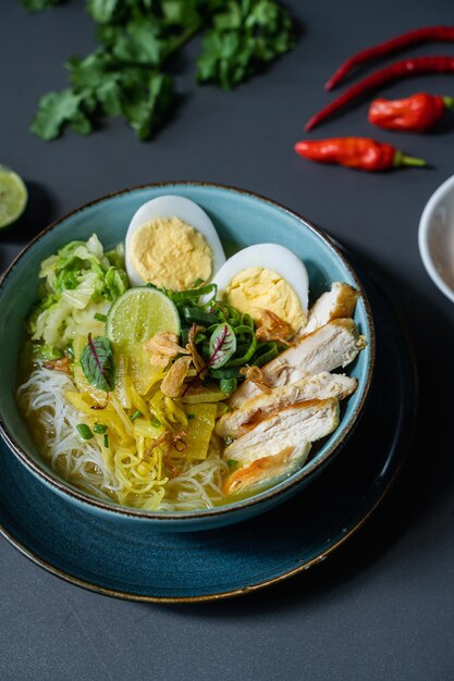 写真 鶏肉、野菜、赤唐辛子が添えられた麺のボウル。