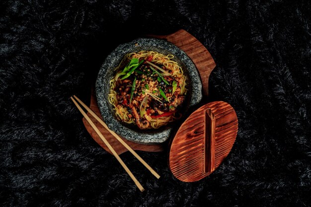 写真 黒い背景に箸の入った麺と木のスプーンの入ったボウル。