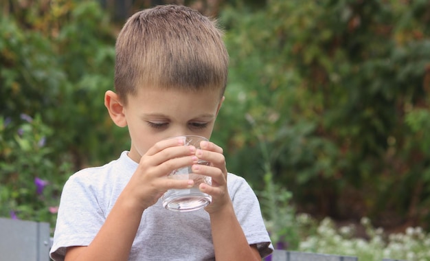 Фото Мальчик пьет воду из стакана на природе селективный фокус природы