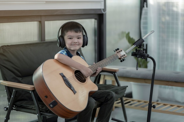 Фото Мальчик учится играть на гитаре, концентрируясь на игре на музыке,