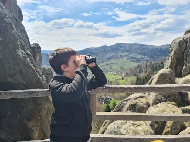 写真 双眼鏡で山を眺める少年